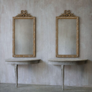 An elegant pair of demi lune consoles with distressed paint